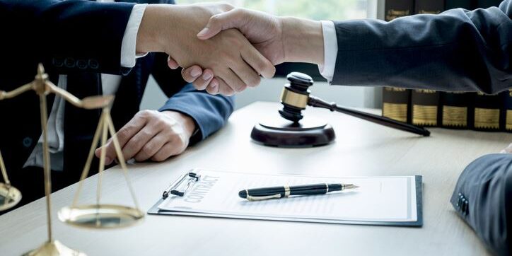 Handshake after Lawyer  providing legal consult business dispute service to the man at the office with justice scale and gavel hammer.